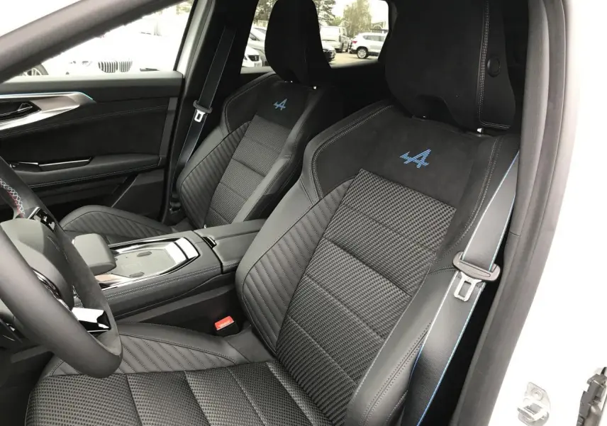 Vue intérieure côté conducteur du Renault Austral blanc, sièges sport noirs avec logo Alpine bleu brodé.