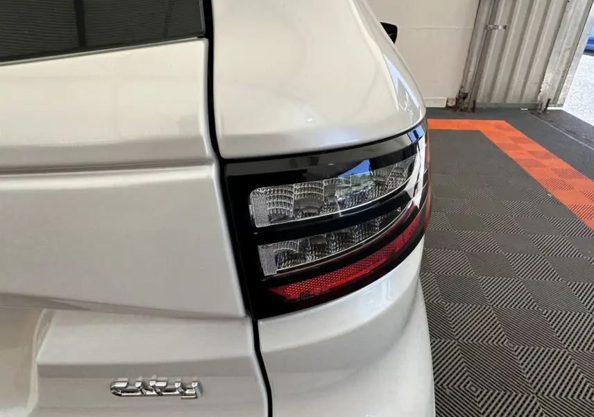 Gros plan sur le feu arrière droit blanc brillant de l'AIXAM AMBITION E CITY PACK 2026 avec détails noirs et rouge.