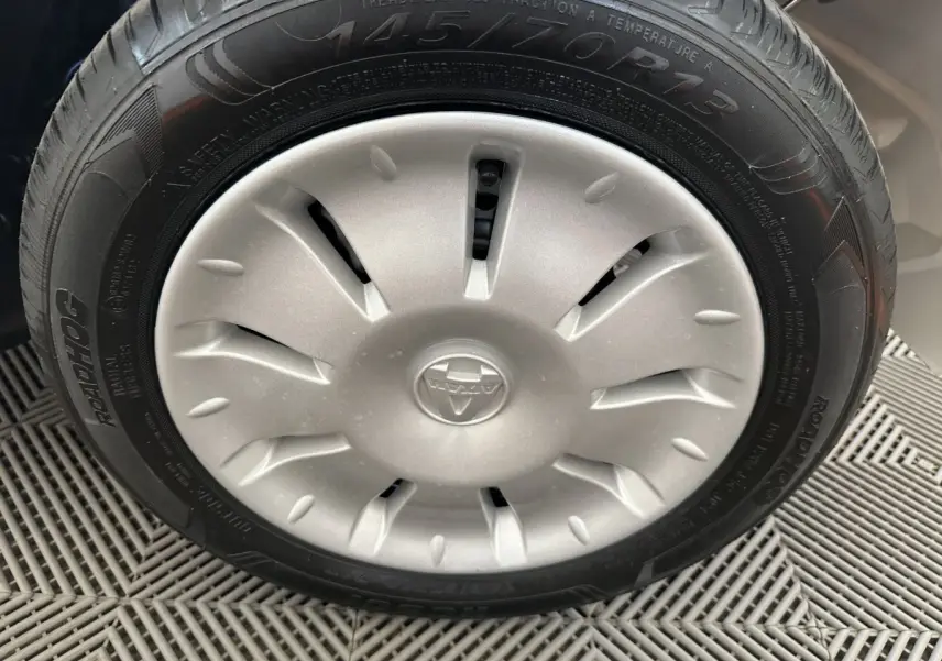 Gros plan sur la roue avant droite d'une Aixam Ambition E City Pack blanche avec jante argentée et logo central.