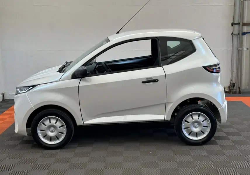 Vue de profil côté gauche d'une Aixam Ambition E City Pack blanche, petite citadine électrique compacte.