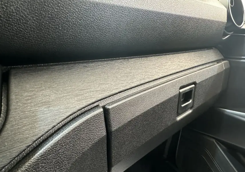 Détail de la boîte à gants noire et de la planche de bord texturée à l'intérieur de l'AIXAM AMBITION E CITY PACK 2026.