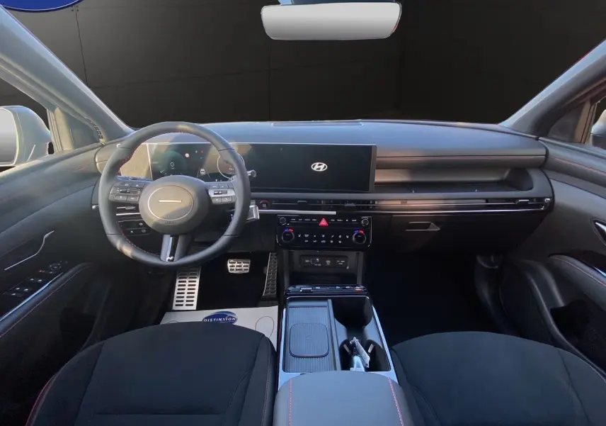 Vue intérieure avant du Hyundai Tucson 2025 noir abyss, avec tableau de bord numérique et volant multifonction.