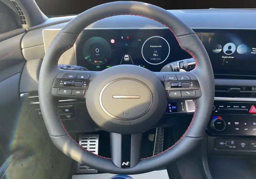 Vue centrée sur le volant N Line noir avec surpiqûres rouges du Hyundai Tucson 2025, tableau de bord digital en arrière-plan.