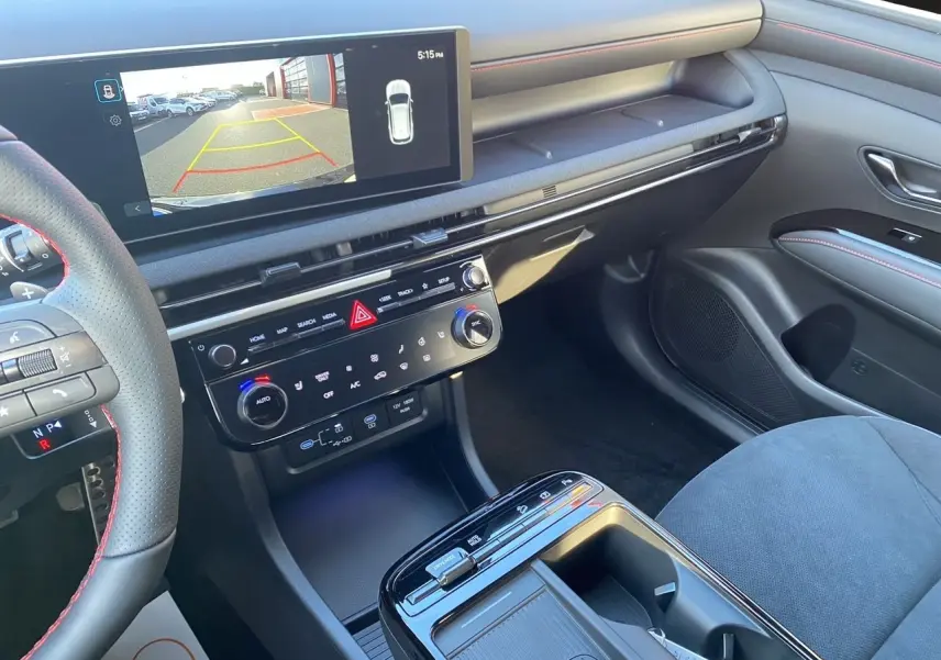 Vue intérieure côté passager du tableau de bord et console centrale du Hyundai Tucson 2025 avec écran tactile et sellerie noire.