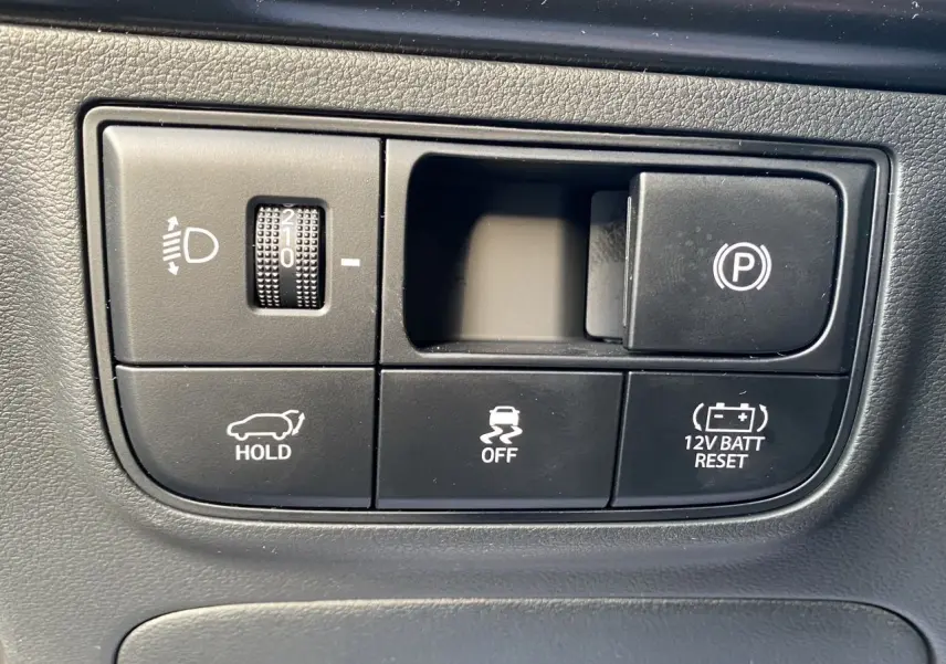 Gros plan sur les commandes noires du tableau de bord du Hyundai Tucson 2025, avec bouton de frein à main électronique.
