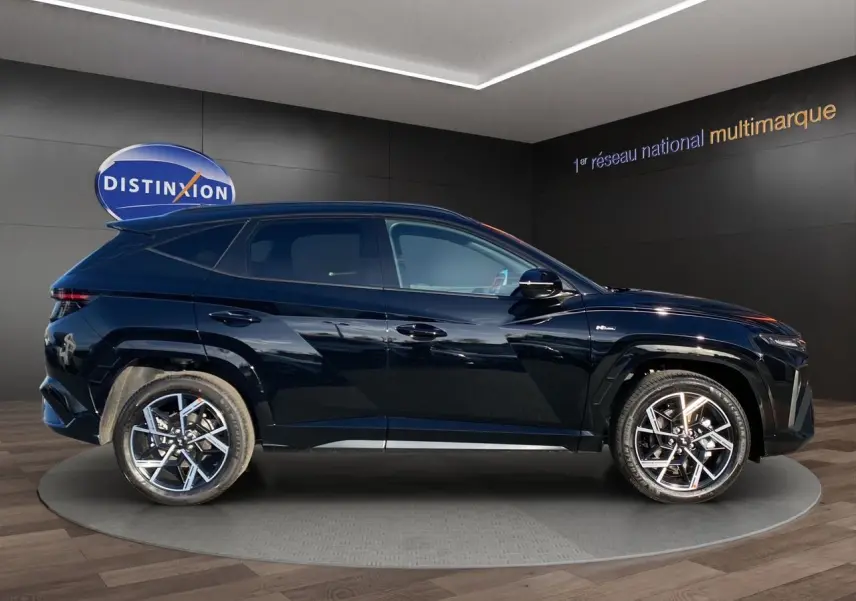 Vue de profil côté gauche du Hyundai Tucson 2025 hybride N Line Creative en noir abyss, avec jantes alliage bicolores distinctives.