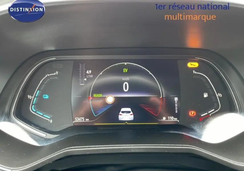 Tableau de bord numérique de Renault Clio blanc glacier, affichage vitesse à 0 km/h et jauges hybrides en vue frontale.