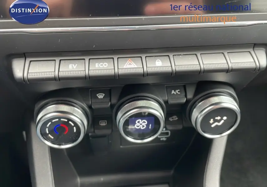 Gros plan sur la console centrale de la Renault Clio blanche, montrant les commandes de climatisation et les boutons de fonction.