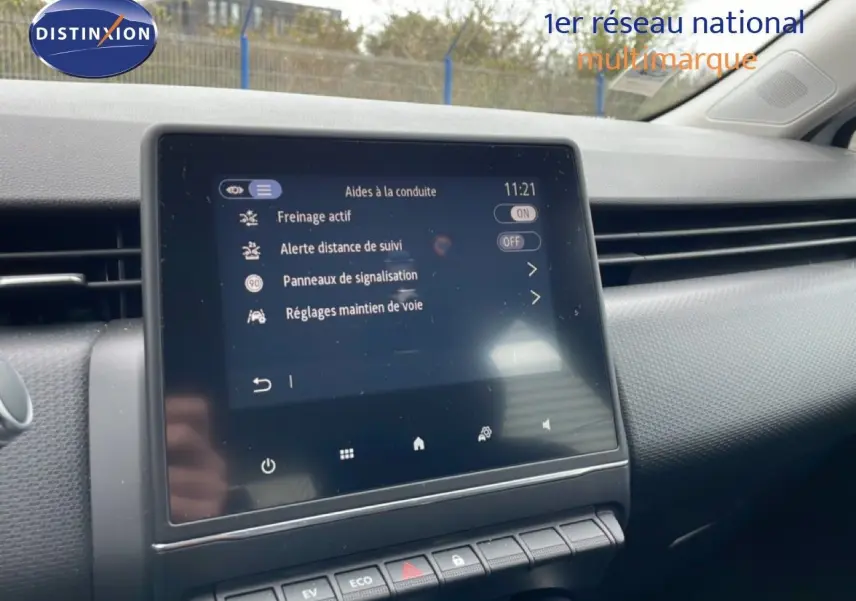 Écran tactile central affichant les aides à la conduite dans l’habitacle d’une Renault Clio blanche Glacier, vue de face.