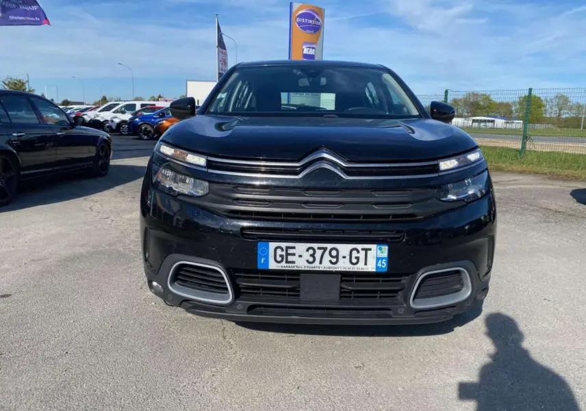 Vue avant d'un Citroën C5 Aircross noir 2021 avec calandre distinctive et feux LED fins sur parking extérieur.