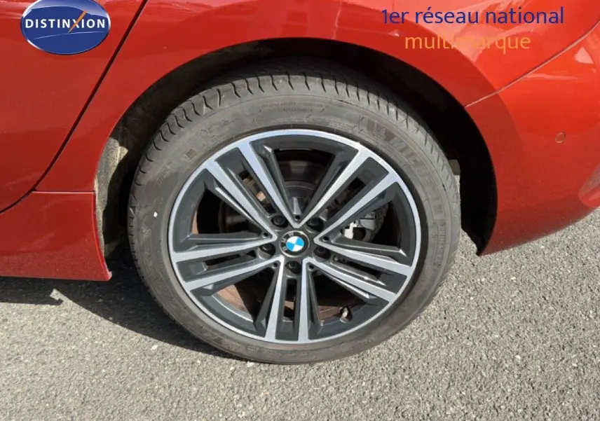 Gros plan sur la roue avant droite d'une BMW Série 1 116i orange Sunset avec jante alliage bicolore.
