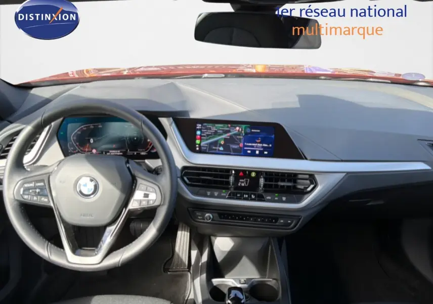Vue intérieure avant de la BMW Série 1 116i 2022, tableau de bord moderne avec écran central et volant multifonction noir.