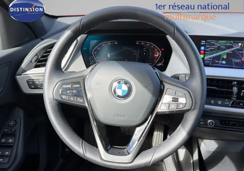 Vue intérieure centrée sur le volant noir de la BMW Série 1 116i 2022 avec tableau de bord numérique et écran tactile.