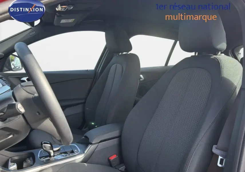 Vue intérieure côté conducteur de la BMW Série 1 116i 2022 avec sièges tissu noirs et console centrale moderne.