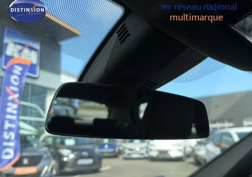 Rétroviseur intérieur de BMW Série 1 116i 2022, vue depuis l’habitacle avec reflet flou du parking extérieur.