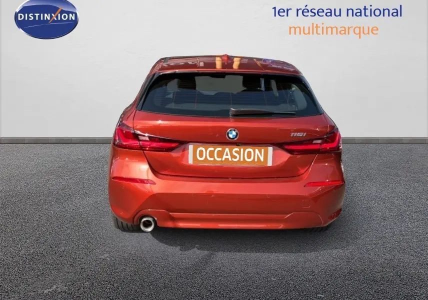 Vue arrière d'une BMW Série 1 116i orange Sunset Metal avec feu LED et sortie d'échappement visible.