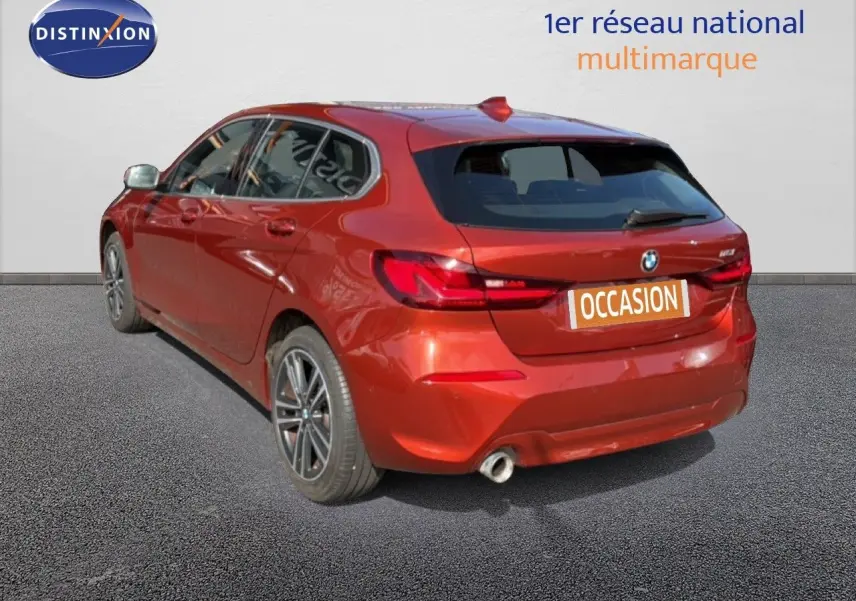 Vue 3/4 arrière droite d'une BMW Série 1 116i Business en orange Sunset métallisé avec jantes alliage et échappement simple.