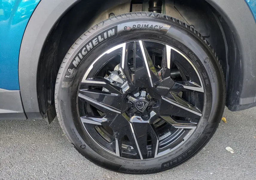Gros plan sur la roue avant gauche d’un Peugeot 3008 Hybrid 145 GT bleu obsession avec jante noire et argentée.