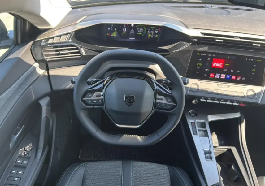 Vue intérieure centrée sur le volant cuir et le tableau de bord numérique du Peugeot 408 Hybrid 145 allure noir.
