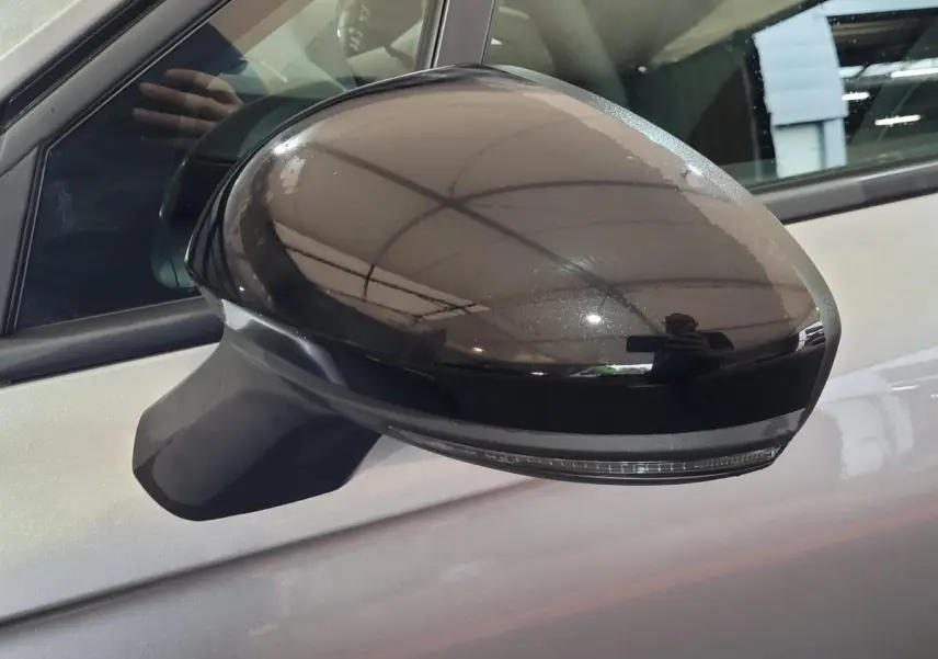 Rétroviseur côté gauche noir brillant sur Renault Clio gris foncé, vue rapprochée sur la portière avant.
