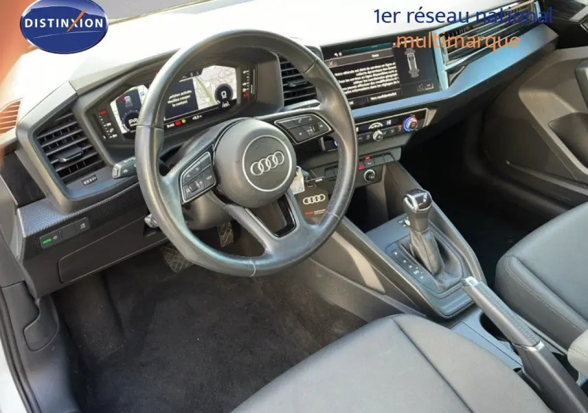 Intérieur de l'Audi A1 Sportback 2023 vu côté conducteur, volant multifonction et console centrale avec boîte auto.