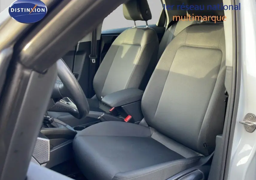 Vue intérieure côté conducteur de l'Audi A1 Sportback 2023 avec sièges tissu gris et portière blanche ouverte.