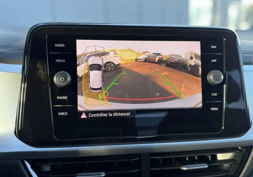 Écran tactile intérieur affichant la caméra de recul du Volkswagen T-Roc gris Indium, avec guidage de trajectoire verte et rouge.