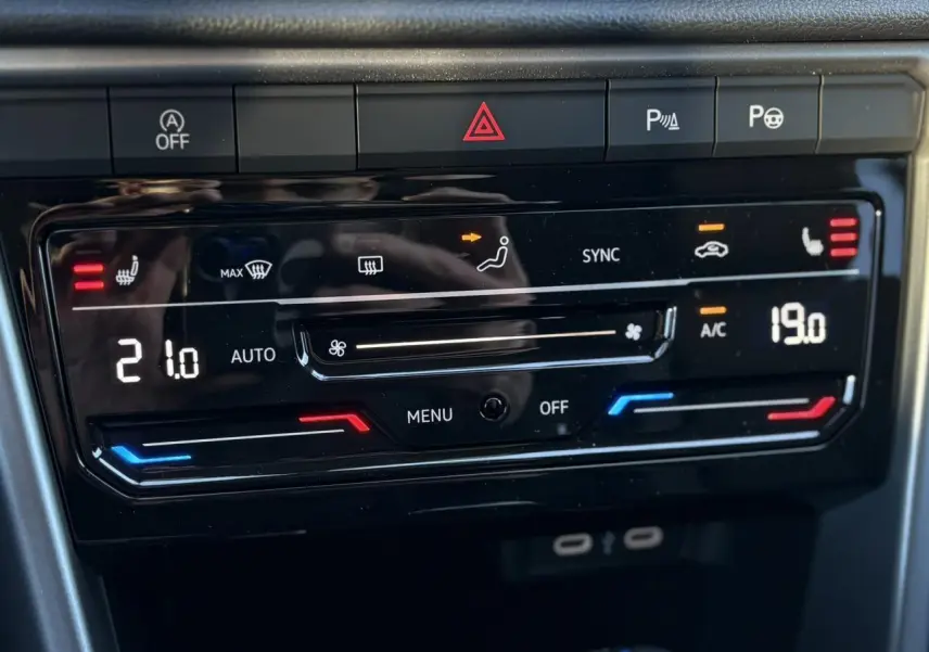 Vue rapprochée de la commande de climatisation bi-zone digitale du Volkswagen T-Roc gris Indium, avec affichage des températures.