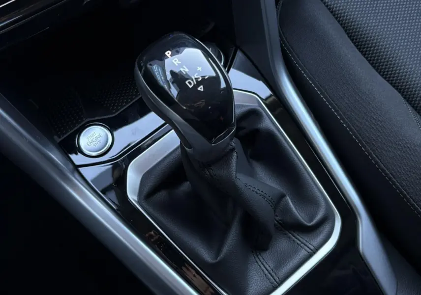 Gros plan sur la commande de boîte automatique noire et le bouton start/stop dans l’habitacle du Volkswagen T-Roc gris.