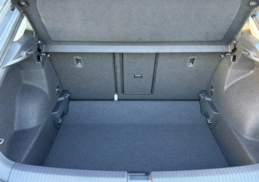 Vue plongeante sur le coffre spacieux et propre du Volkswagen T-Roc gris Indium, avec plancher plat et banquette arrière rabattable.