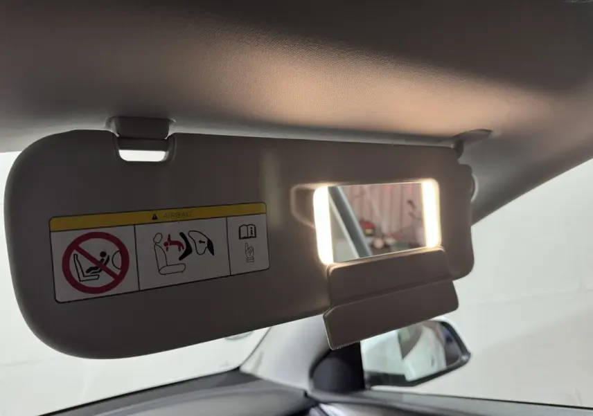 Détail du pare-soleil côté conducteur avec miroir éclairé dans l’habitacle blanc d’un Tesla Model Y 2022.