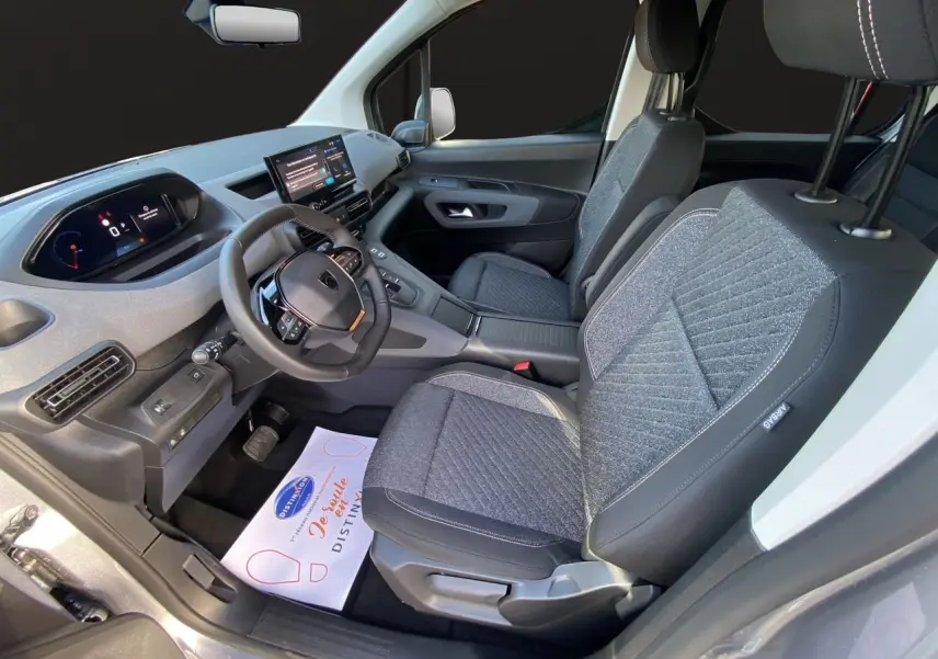 Vue intérieure côté conducteur du Peugeot Rifter gris acier 2026, avec sièges tissu et tableau de bord numérique.