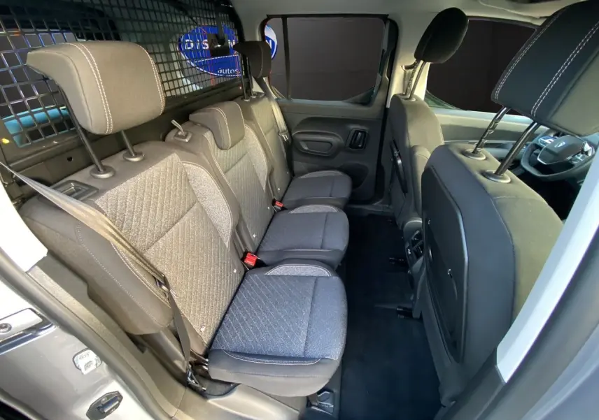 Vue intérieure côté gauche du Peugeot Rifter gris acier 2026, montrant les trois sièges arrière et la cloison de séparation.