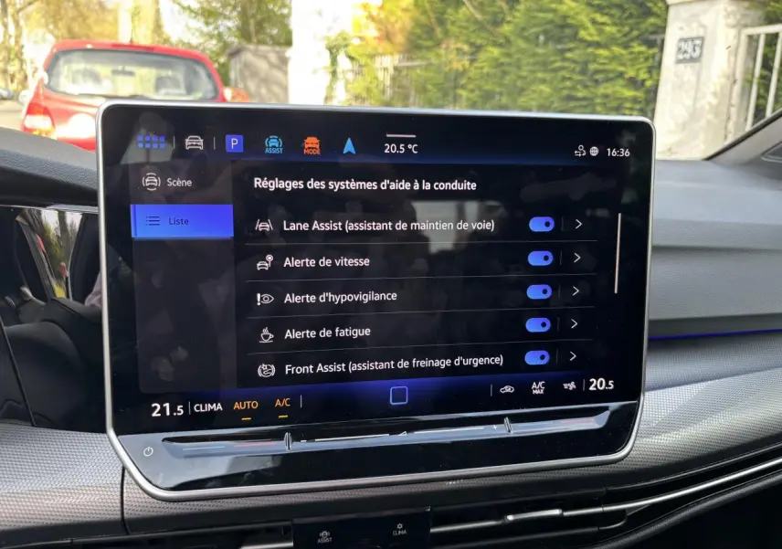 Écran tactile central de la Volkswagen Golf blanche 2024, vue intérieure sur les aides à la conduite activées.