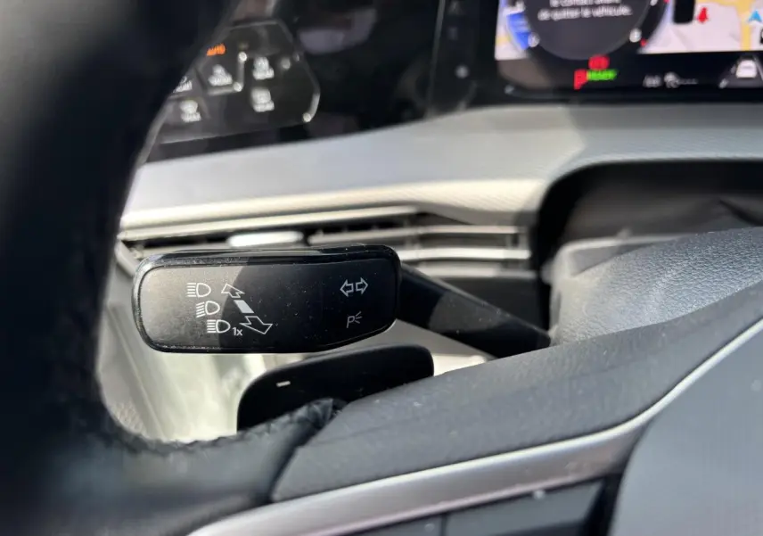 Gros plan sur la manette de clignotant noire dans l’habitacle blanc d’une Volkswagen Golf 1.5 eTSI 2024.