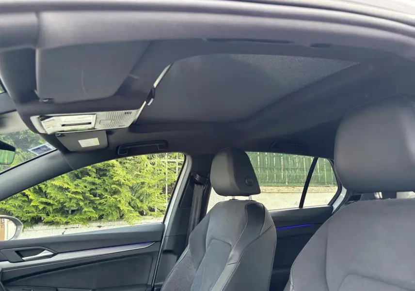 Vue intérieure de la Volkswagen Golf 1.5 eTSI Edition 50, montrant les sièges avant en tissu et cuir noir avec éclairage d'ambiance bleu.