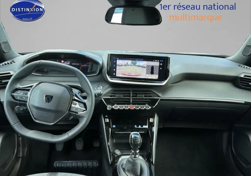 Vue intérieure avant du Peugeot 2008 1.2 100 allure gris artense, mettant en valeur le volant multifonction et l'écran tactile central.
