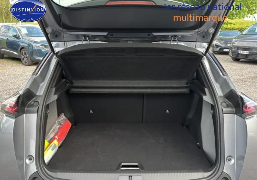 Coffre ouvert vu de l'arrière d'un Peugeot 2008 gris artense avec intérieur noir et cache-bagages relevé.