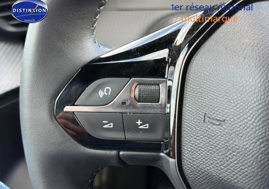 Gros plan sur les commandes gauche du volant cuir du Peugeot 2008 gris artense, boutons multifonctions visibles.