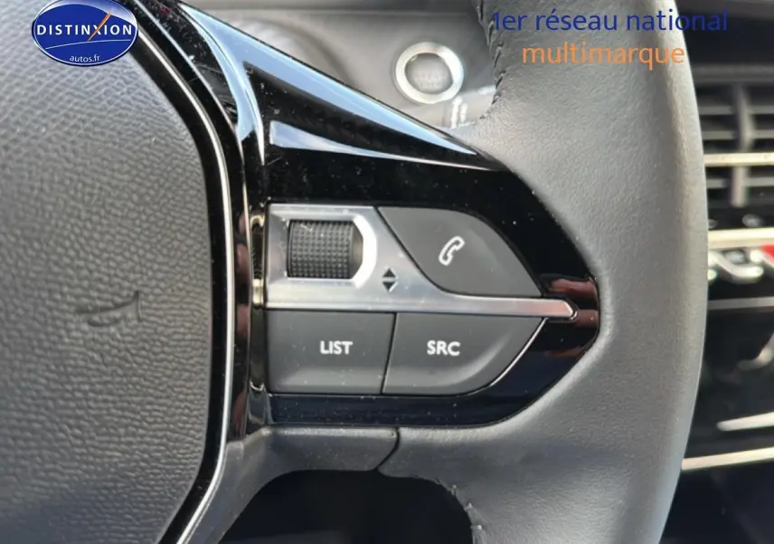 Gros plan sur les commandes gauche du volant noir du Peugeot 2008 gris artense, avec boutons multifonctions et molette.