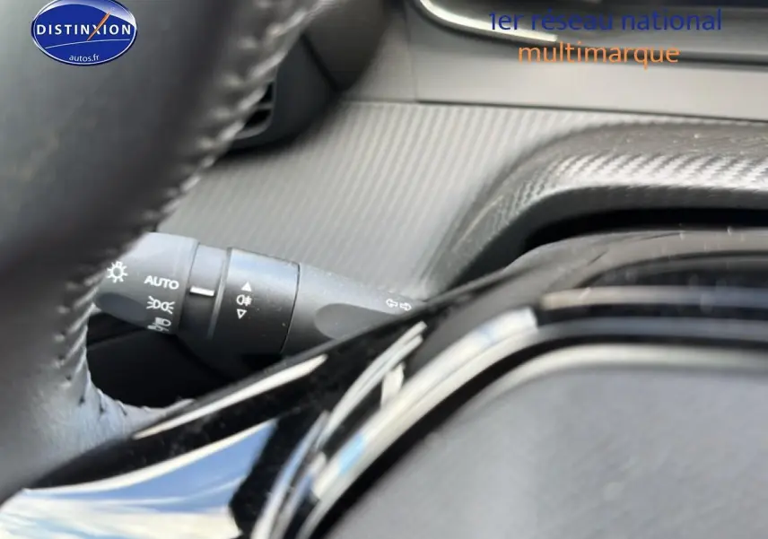 Gros plan sur la commande des phares à gauche du volant dans l’habitacle gris du Peugeot 2008 1.2 100 Allure 2025.