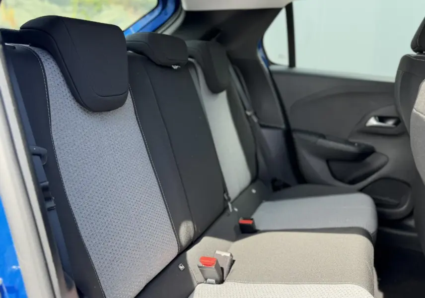Vue latérale intérieure des sièges arrière de la Opel Corsa 2025 bleu Voltaic avec tissu bicolore gris et noir.