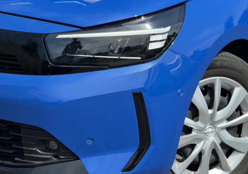 Gros plan sur l'avant droit bleu Voltaic de l'Opel Corsa 2025, mettant en valeur le phare LED et la jante alliage.