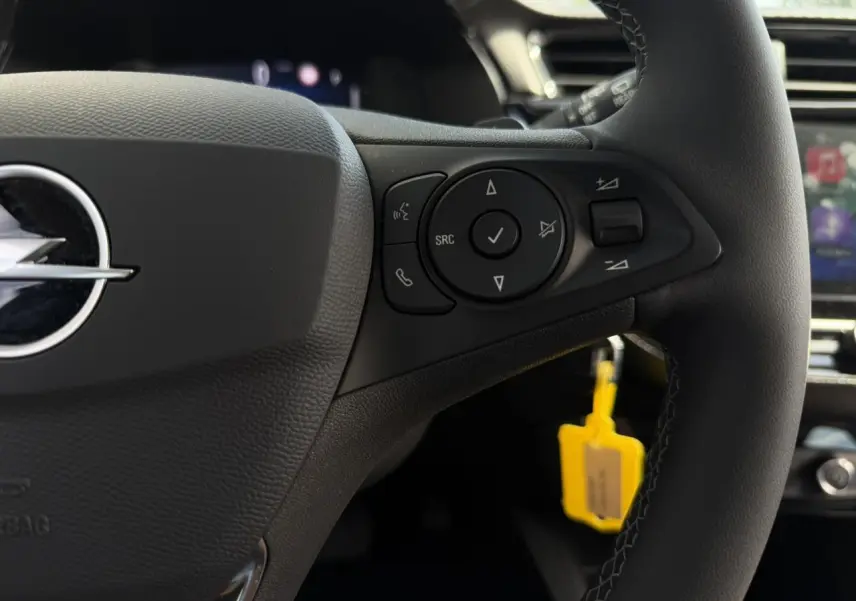 Gros plan sur le volant multifonction noir de l’Opel Corsa 2025 avec commandes intégrées et logo Opel visible.