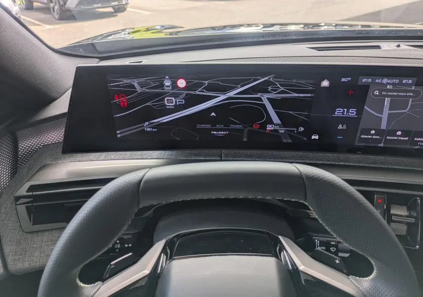 Vue intérieure du tableau de bord du Peugeot 3008 Hybrid 145 GT 2025, écran numérique large avec navigation et climatisation affichée.