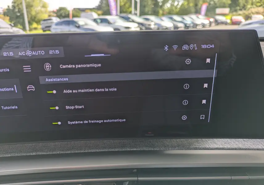 Écran tactile intérieur du Peugeot 3008 Hybrid 145 GT affichant les assistances à la conduite, avec tableau de bord et reflet extérieur.