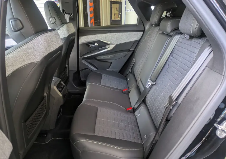 Vue intérieure côté droit des sièges arrière du Peugeot 3008 Hybrid 145 GT noir avec sellerie tissu embossée et surpiqûres claires.