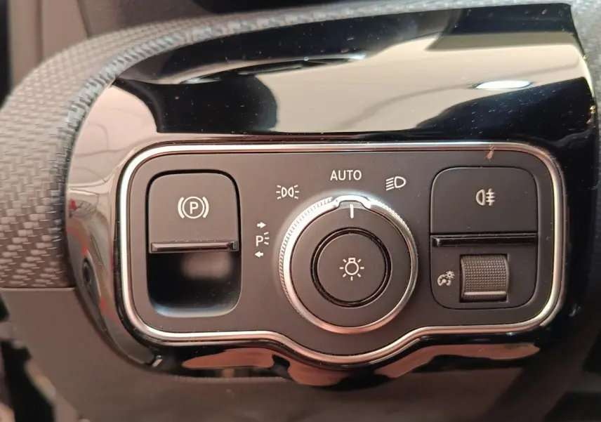 Gros plan sur le panneau de commandes d’éclairage et frein à main électrique de la Mercedes Classe A noire.