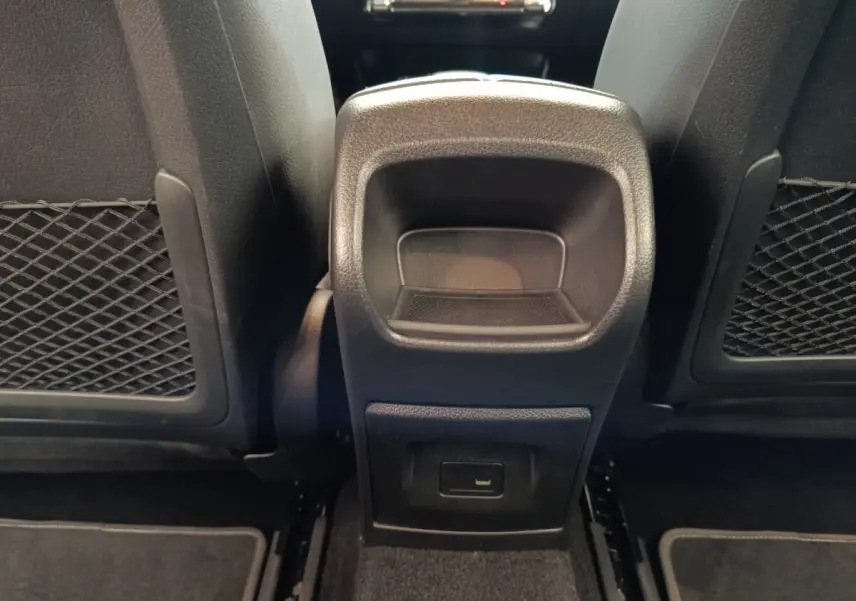 Vue rapprochée de la console centrale arrière noire entre les sièges avant d'une Mercedes Classe A 250 e Business Line.