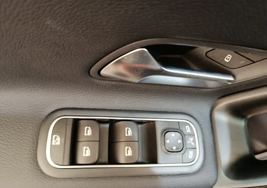 Gros plan sur la commande des vitres électriques et poignée intérieure en métal dans une Mercedes Classe A noire.